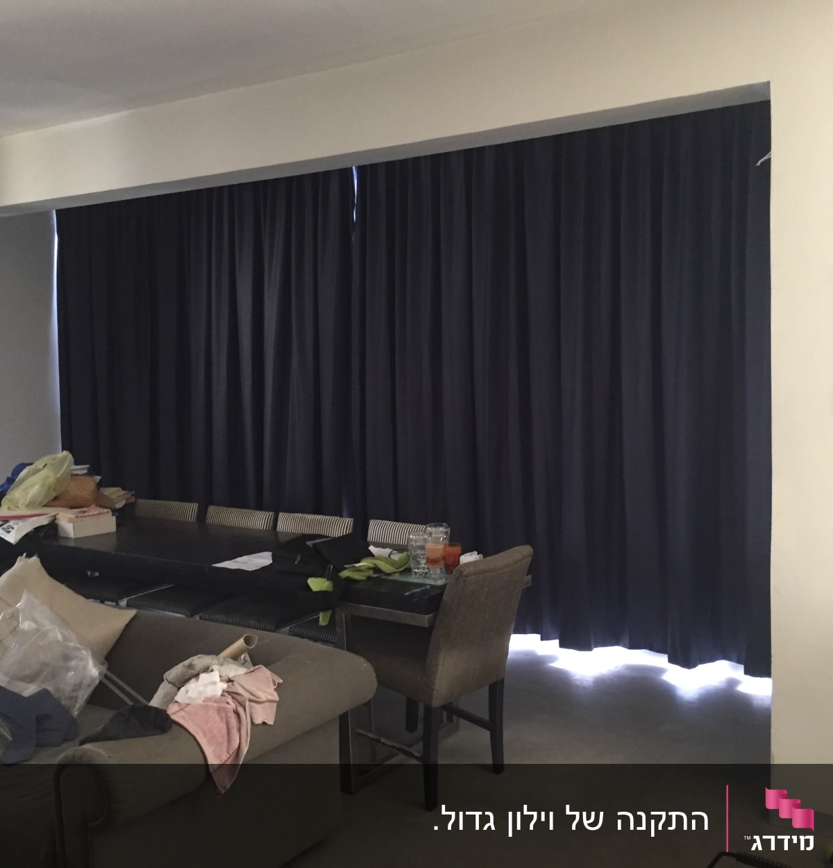 וילון כהה תלוי על חלון גדול בסלון